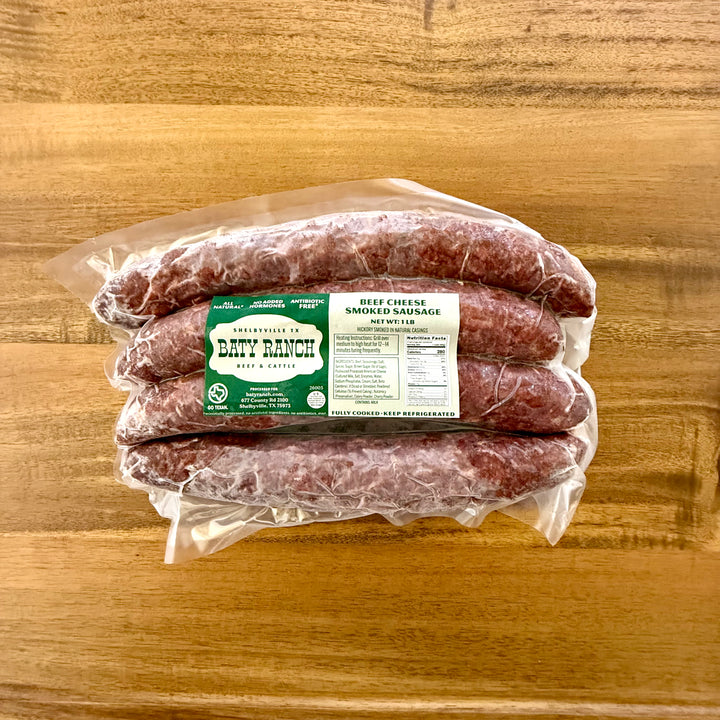 Packaged beef and cheese sausages with a label on a wooden surface