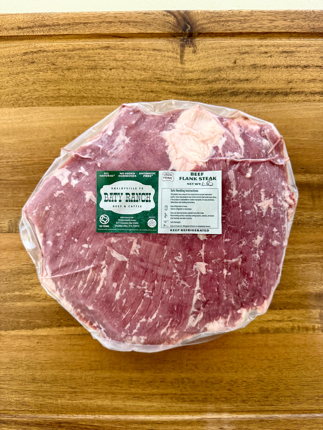 Packaged raw meat on a wooden surface with a label