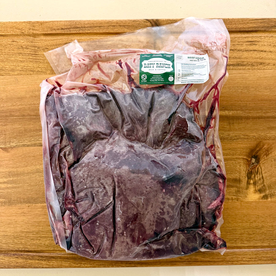 Packaged beef liver on a wooden cutting board with a label