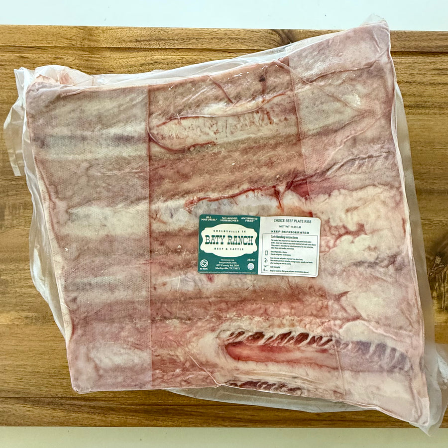 Vacuum-sealed package of beef plate ribs on a wooden surface with a label.