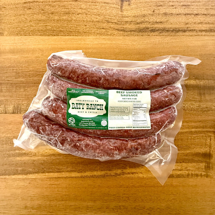 Packaged beef smoked sausages with a label on a wooden surface