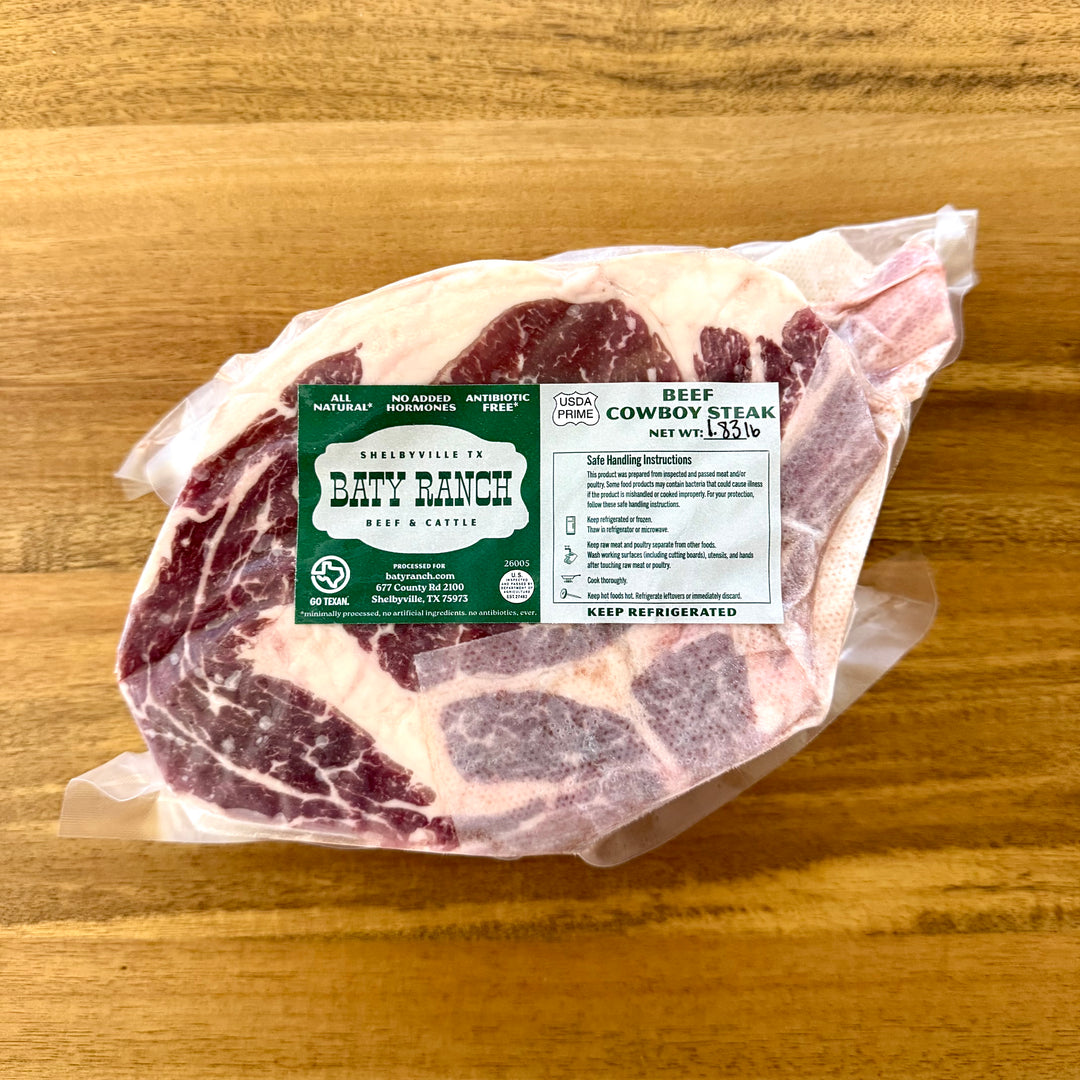 Raw beef cowboy steak with a label on a wooden surface