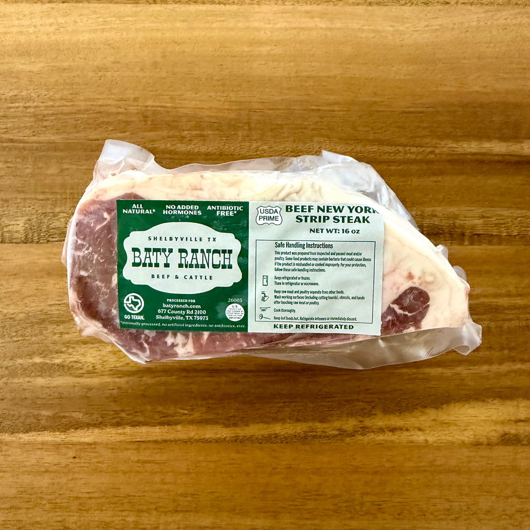 Packaged beef New York strip steak with Baty Ranch label on a wooden surface