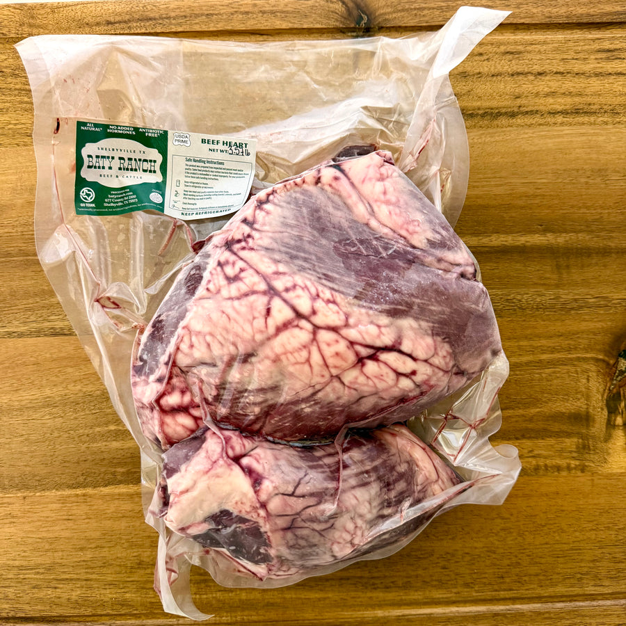 Raw beef hearts in a clear plastic bag with a label on a wooden surface