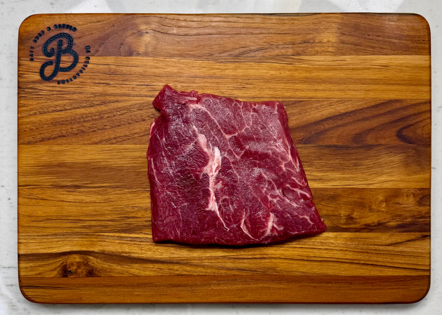 Raw Flat Iron steak on wooden cutting board.