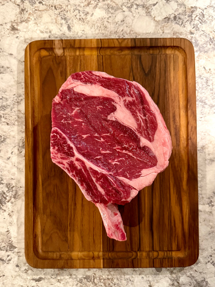 Raw steak on a wooden cutting board with a marble countertop background