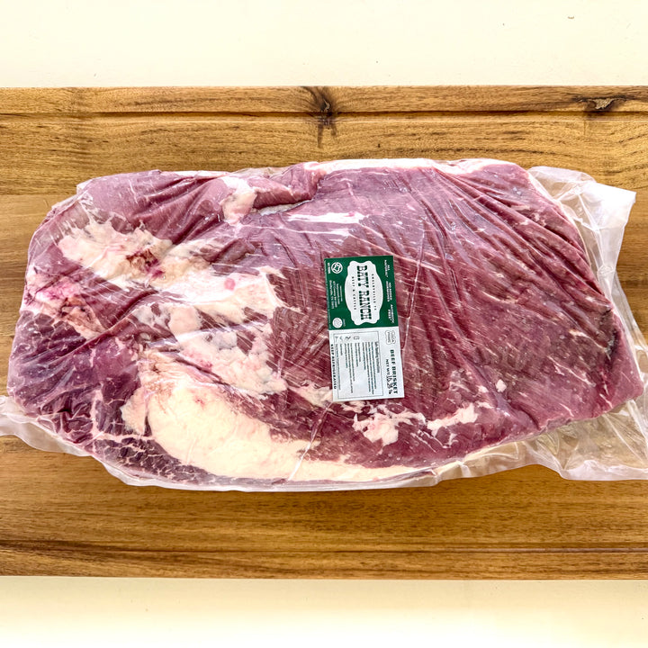 Packaged raw beef brisket with a label on a wooden surface