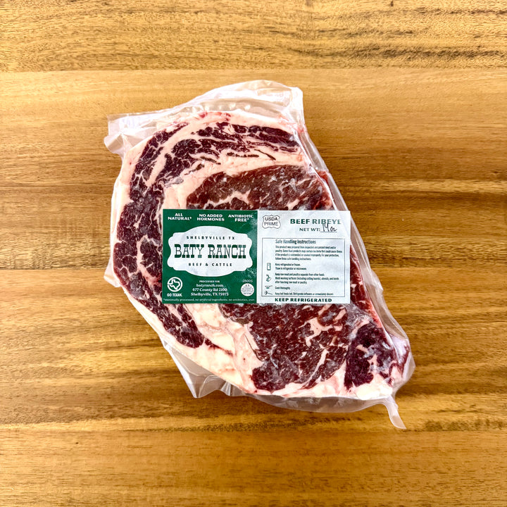 Packaged beef ribeye on a wooden surface with Baty Ranch Beef label.