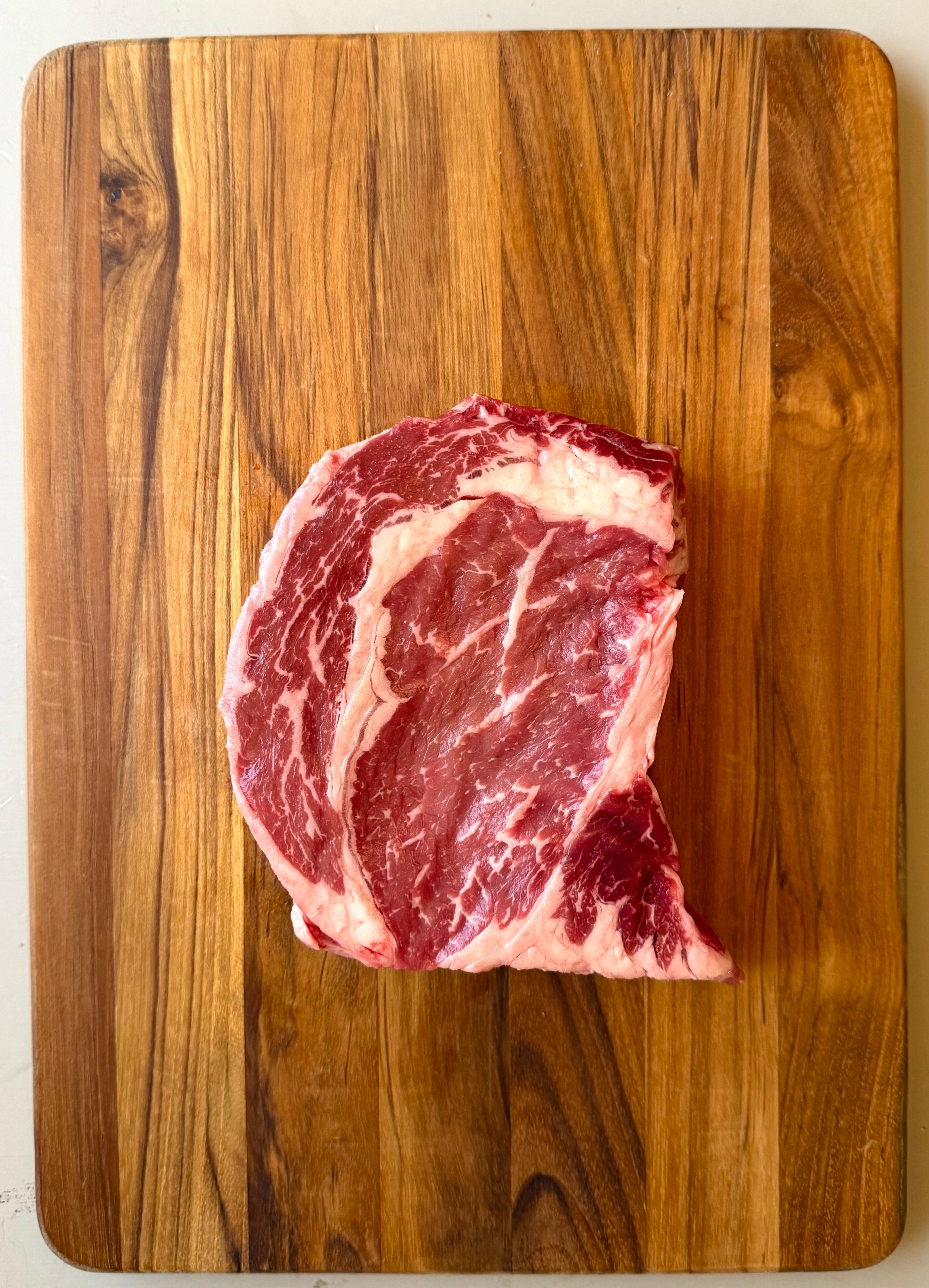 Raw Beef Ribeye steak on a wooden cutting board
